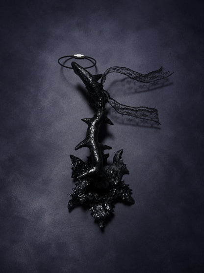 Reverse view of Thorn Bloom Talisman with a black thorned stem, sculptural bloom and trailing lace.